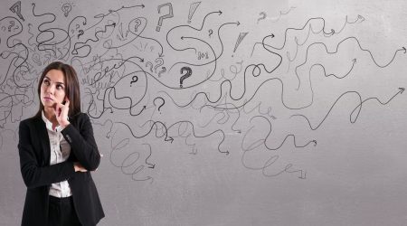 Thoughtful,Businesswoman,With,Abstract,Arrows,Sketch,On,Concrete,Wall,Background.